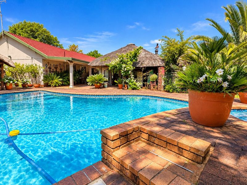 A well-maintained outdoor pool area featuring a swimming pool, brick paving, and a thatched lapa, perfect for outdoor entertaining.