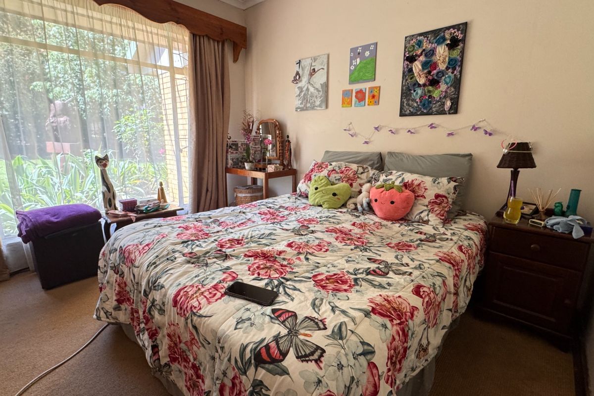 A cozy bedroom featuring carpeted flooring and a large sliding glass door that provides ample natural light and views of the garden.