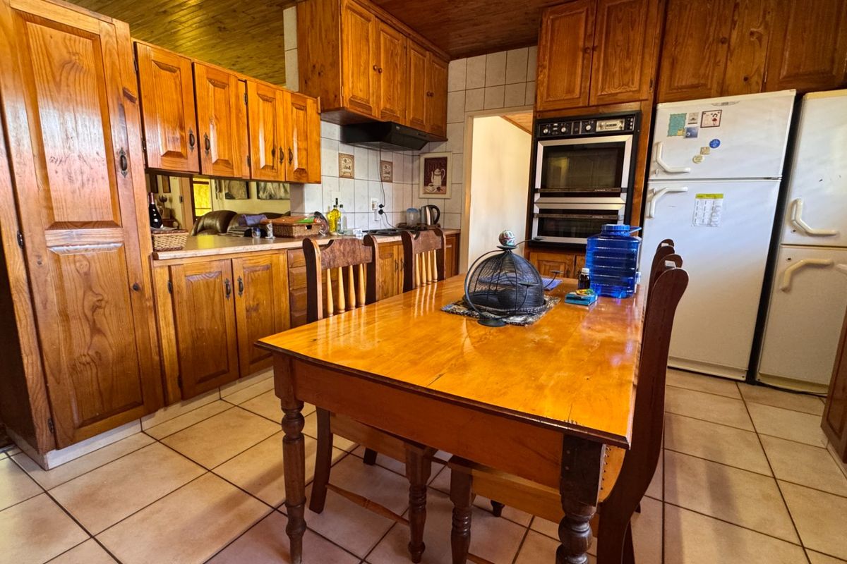 A traditional kitchen featuring extensive wooden cabinetry, a built-in double oven, extractor fan, tiled backsplash, and warm wooden ceiling finishes.