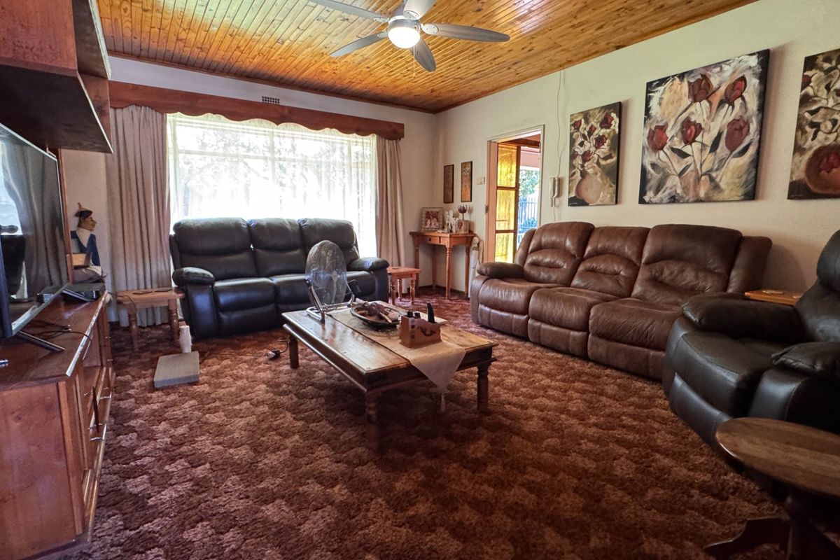 Spacious living room featuring a warm timber tongue and groove ceiling, ceiling fan, and large window allowing for natural light.