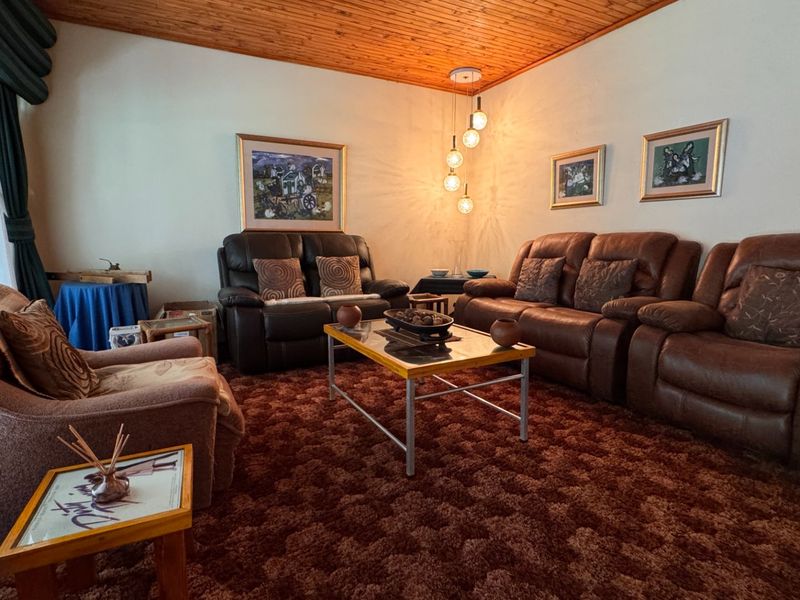 A living room featuring a warm timber tongue and groove ceiling and pendant lighting, offering a dated aesthetic ready for modern updates.