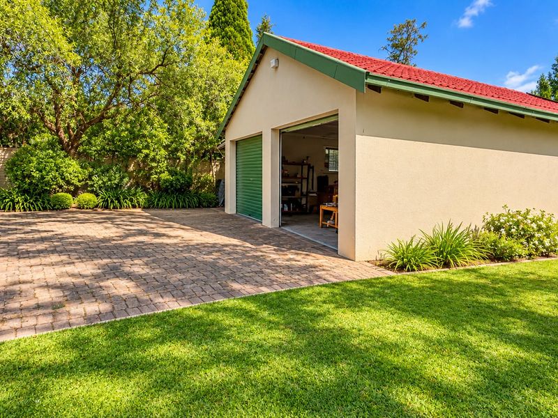 A well-maintained double garage featuring roller shutter doors, set within a neat garden with a paved driveway.