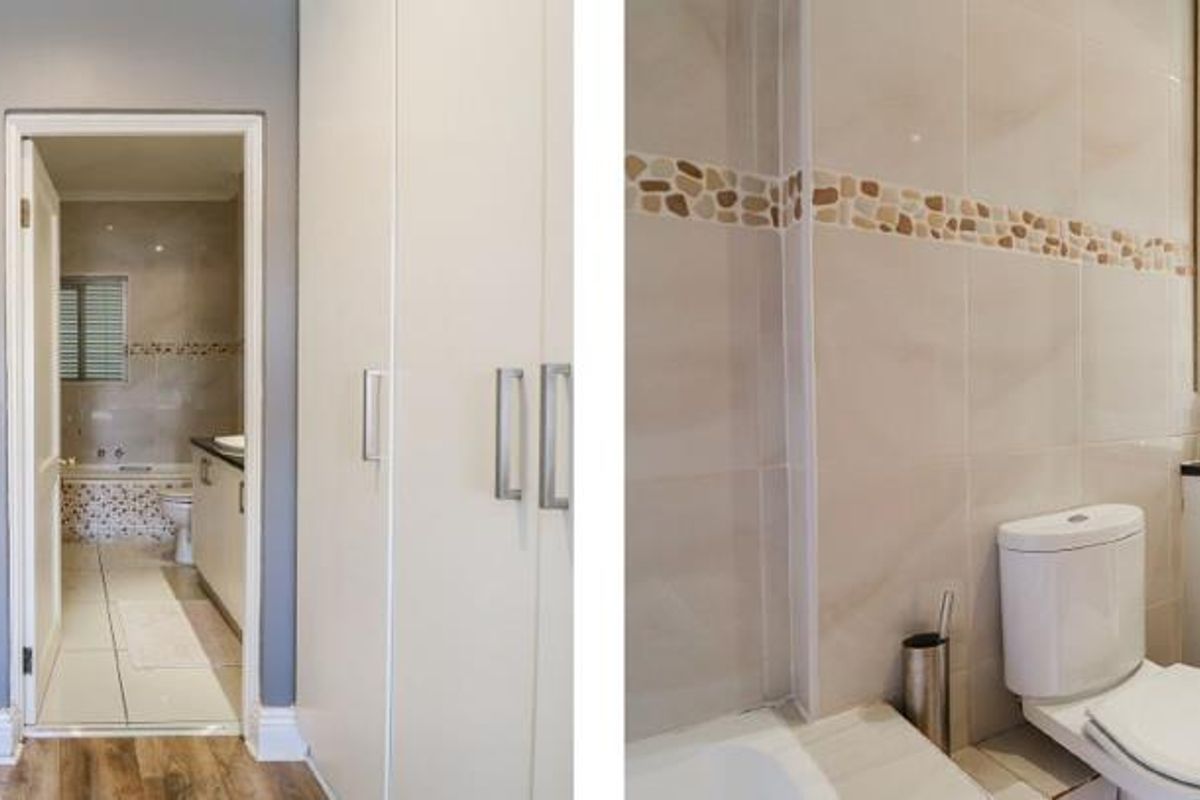 A bathroom featuring a double vanity, tiled walls, and built-in storage cupboards, with an adjacent dressing area.
