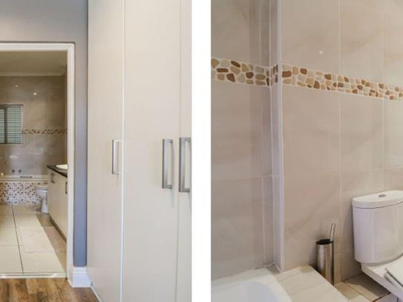 A bathroom featuring a double vanity, tiled walls, and built-in storage cupboards, with an adjacent dressing area.