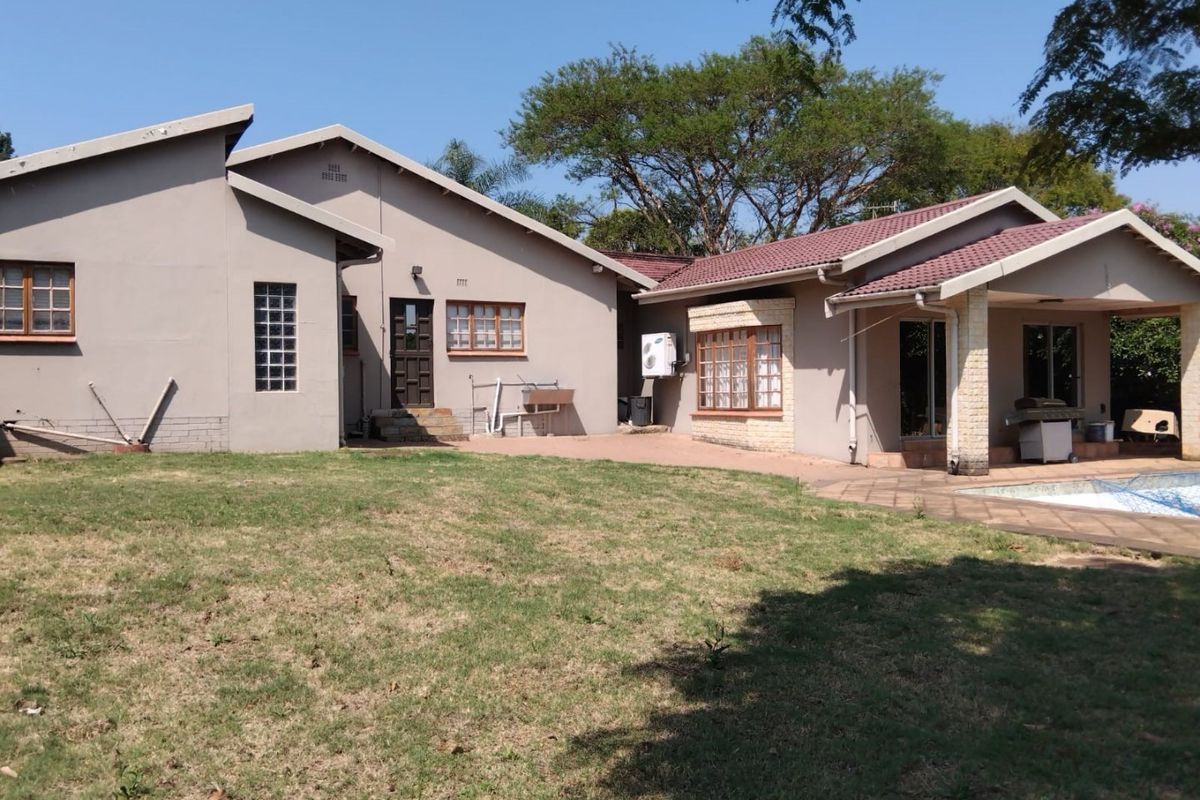 Rear view of the house featuring a paved patio area, swimming pool, and established garden with a tiled roof and exterior wall finishes.