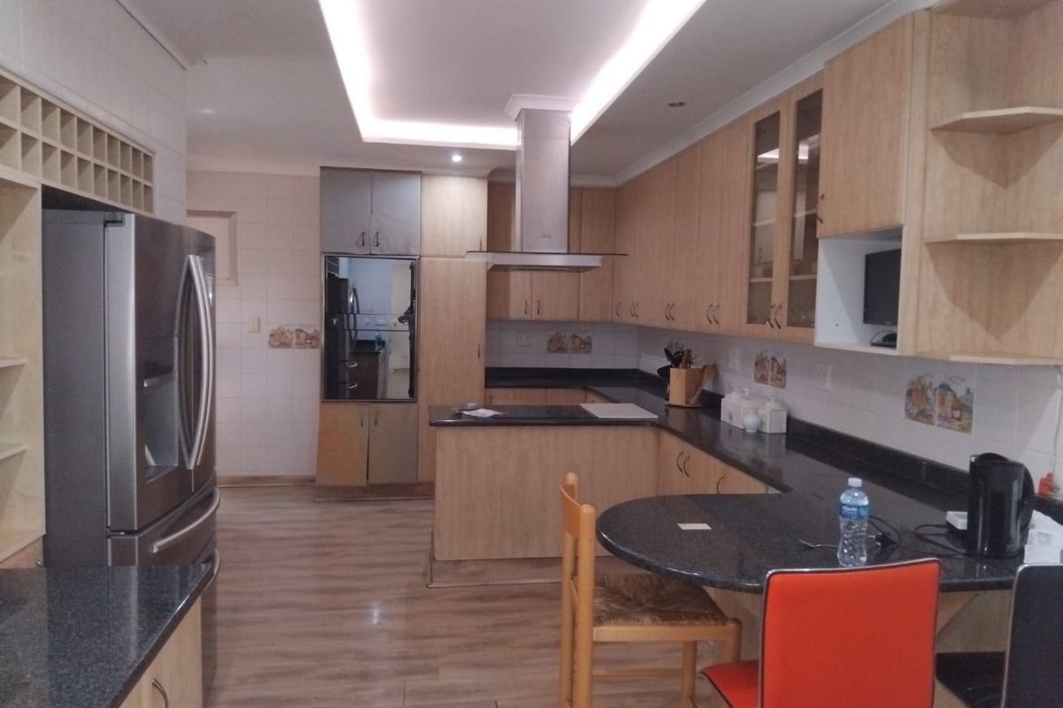 A well-appointed kitchen featuring light wood cabinetry, dark granite countertops, a breakfast nook, and modern recessed ceiling lighting.