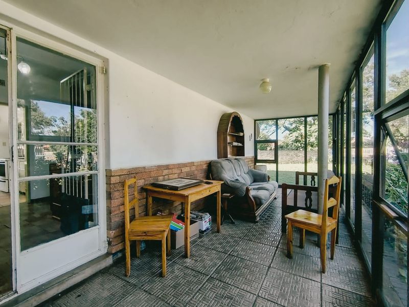 Enclosed patio area featuring exposed brickwork, tiled flooring, and large windows providing natural light and garden views.