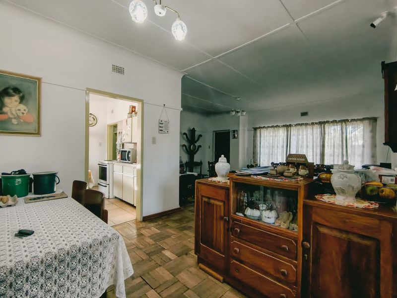 Open plan living and dining area featuring traditional parquet flooring and an adjacent kitchen with built-in cabinetry and a freestanding stove.