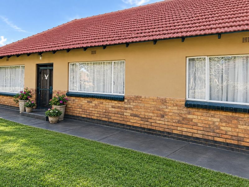 Front elevation of a well-maintained house featuring a tiled roof, brick facade, and secure window bars with a paved walkway.