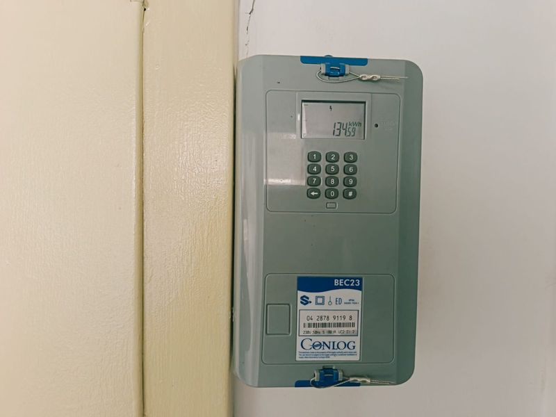 A wall-mounted prepaid electricity meter installed in a utility area.