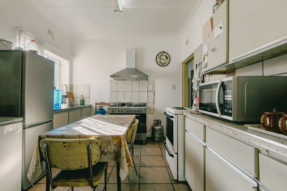 A functional kitchen featuring tiled flooring, built-in cabinetry, and a gas stove with an extractor fan, offering a practical layout for daily meal preparation.