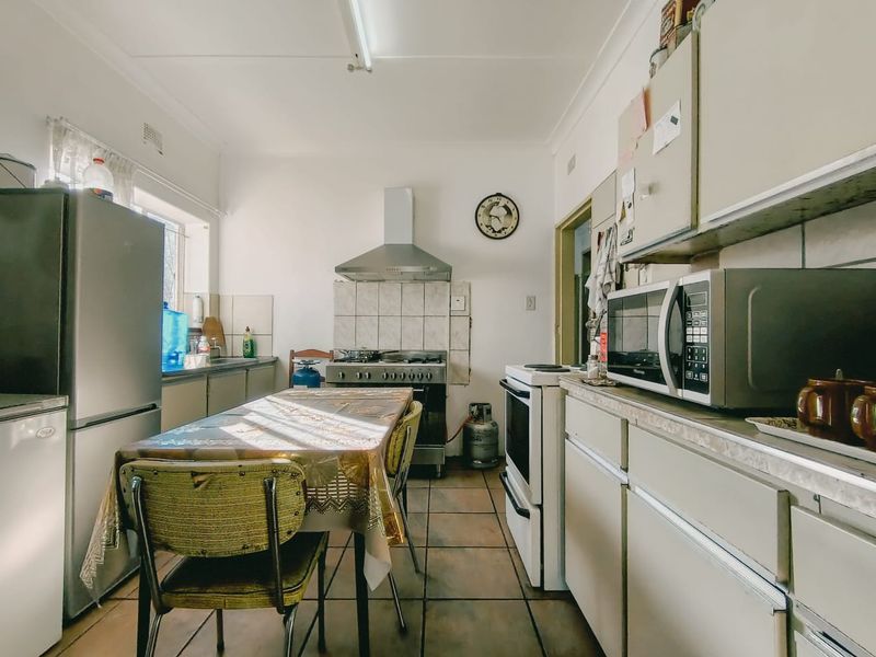 A functional kitchen featuring tiled flooring, built-in cabinetry, and a gas stove with an extractor fan, offering a practical layout for daily meal preparation.