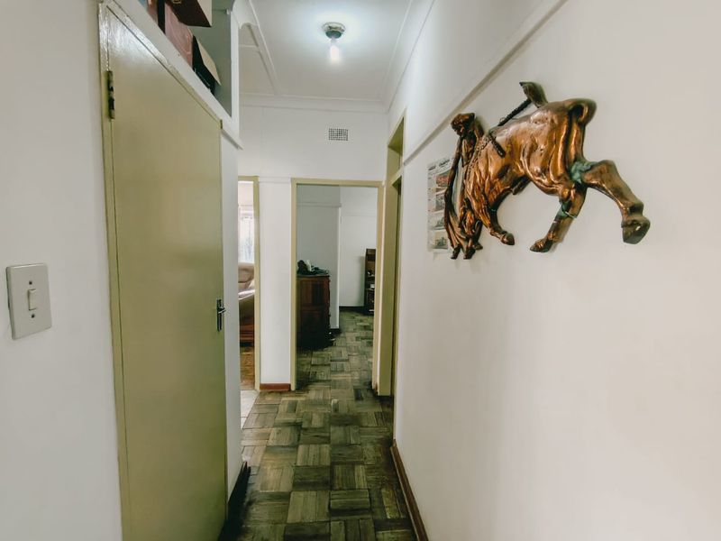 A functional hallway featuring classic parquet flooring and a built-in storage cupboard, providing access to adjacent rooms within the home.
