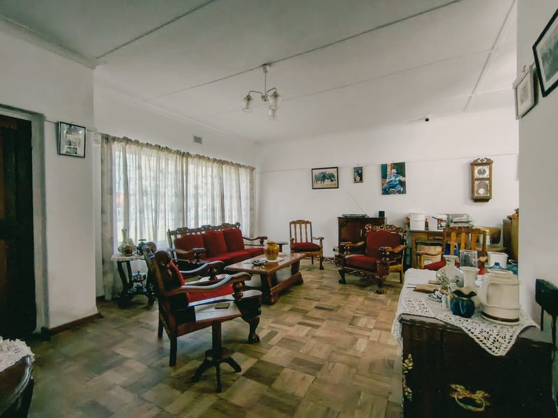 Spacious living room featuring traditional parquet flooring, classic ceiling cornicing, and large windows allowing for natural light.