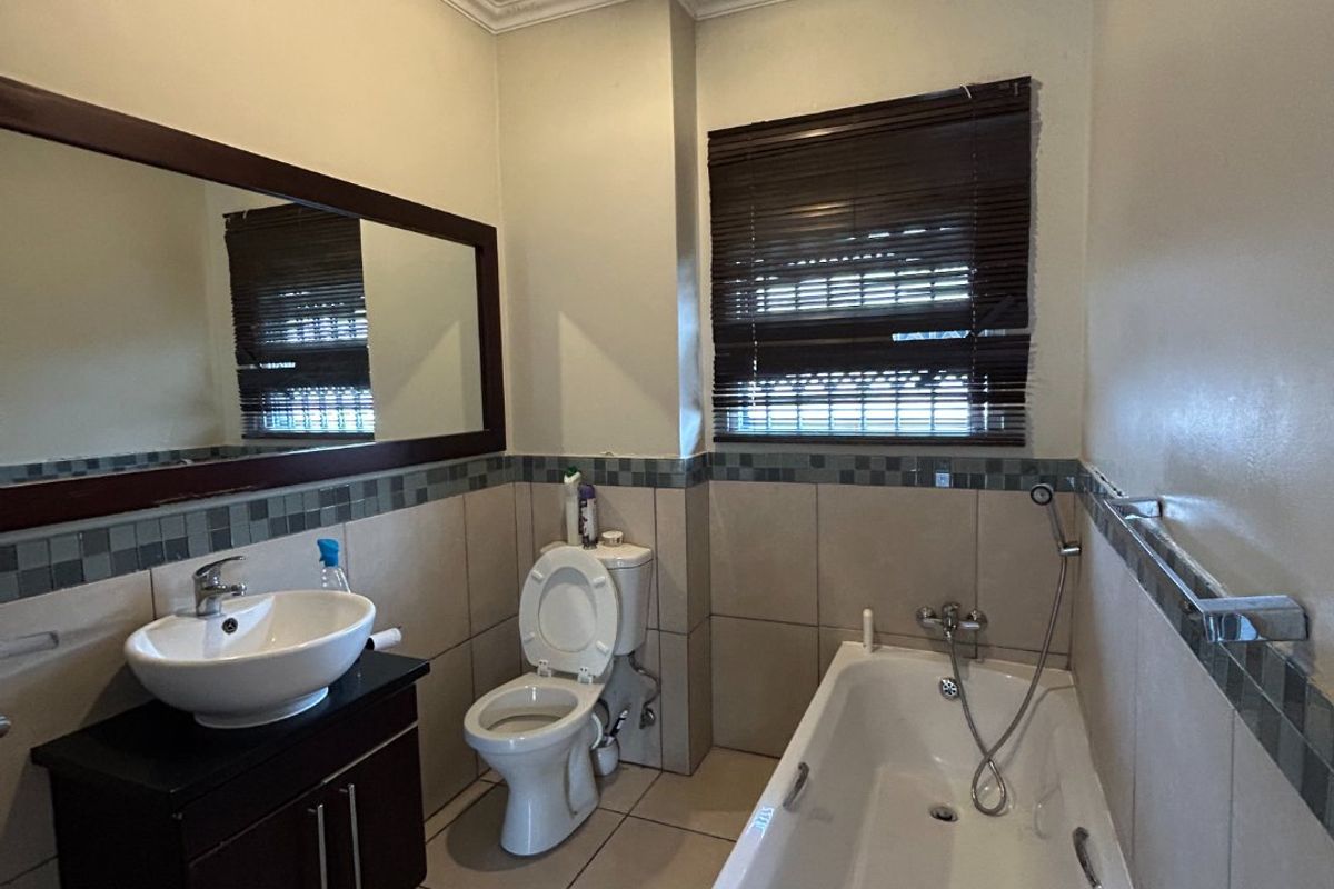 A bathroom featuring a vanity with vessel sink, toilet, and bathtub with handheld shower mixer, requiring attention to ceiling maintenance.