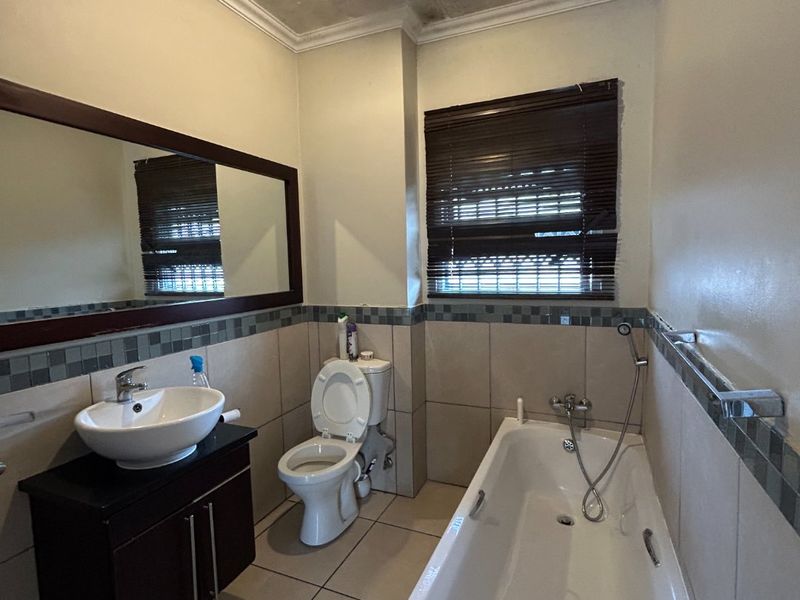 A bathroom featuring a vanity with vessel sink, toilet, and bathtub with handheld shower mixer, requiring attention to ceiling maintenance.