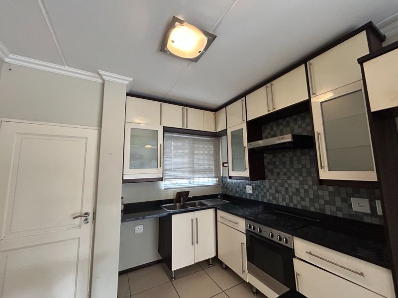 A functional kitchen featuring built-in cabinetry, granite countertops, a stainless steel oven with hob, and a tiled backsplash.