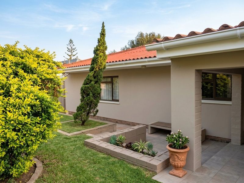 A well-maintained rear exterior view featuring a paved patio area, brick planter boxes, and a tiled roof with integrated guttering.