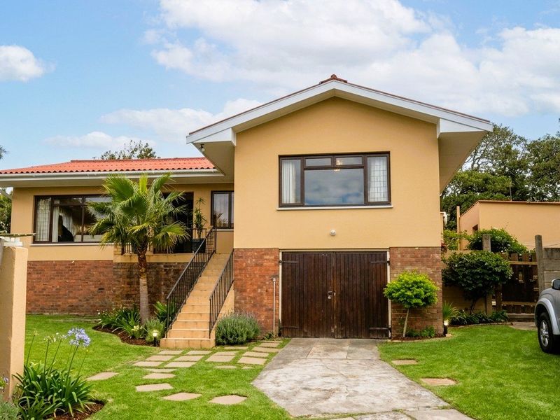 A well-maintained single-story house featuring a brick and plaster facade, a tiled roof, an integrated garage, and a landscaped front garden with a paved driveway.