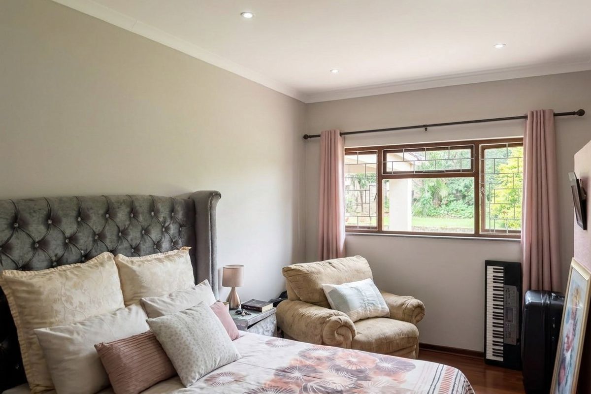 A well-maintained bedroom featuring laminate flooring, leaded glass windows, and recessed downlighting, offering a comfortable and neutral living space.