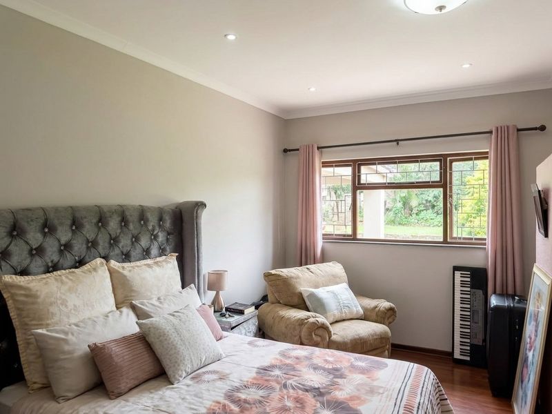 A well-maintained bedroom featuring laminate flooring, leaded glass windows, and recessed downlighting, offering a comfortable and neutral living space.