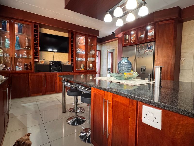 Spacious kitchen featuring dark wood cabinetry, granite countertops, a central island, and integrated display shelving, offering a warm and functional culinary space.
