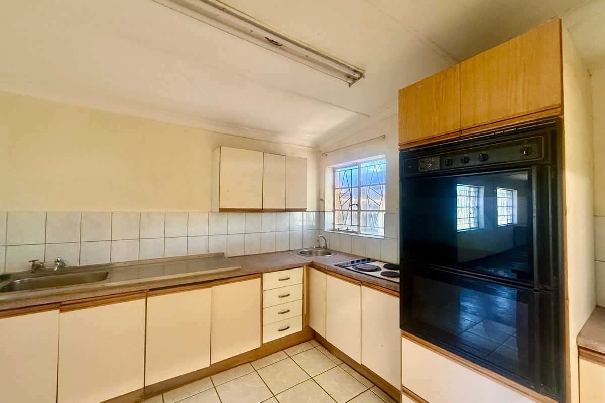 A functional kitchen featuring built-in cabinetry, a double sink, an integrated oven, and an electric hob, offering a blank canvas for modern renovation.