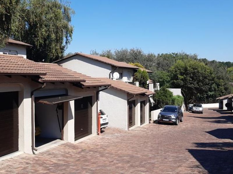 Exterior view of an apartment complex featuring a paved driveway and multiple garage units with tiled roofing.