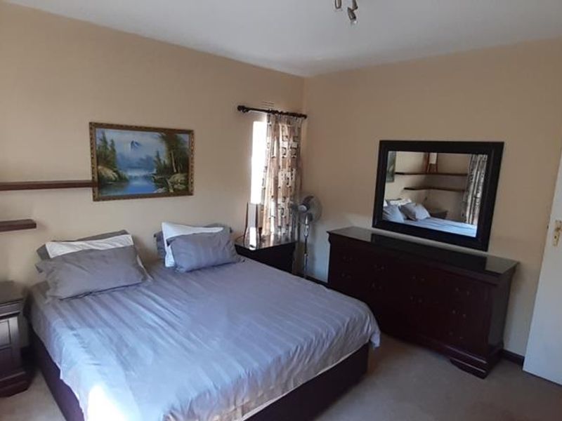 A standard bedroom featuring neutral wall tones, carpeted flooring, and built-in wall shelving.
