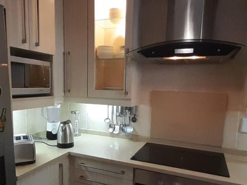 Modern kitchen featuring sleek cabinetry, integrated appliances including a hob and extractor fan, and elegant under-cabinet lighting for a functional workspace.