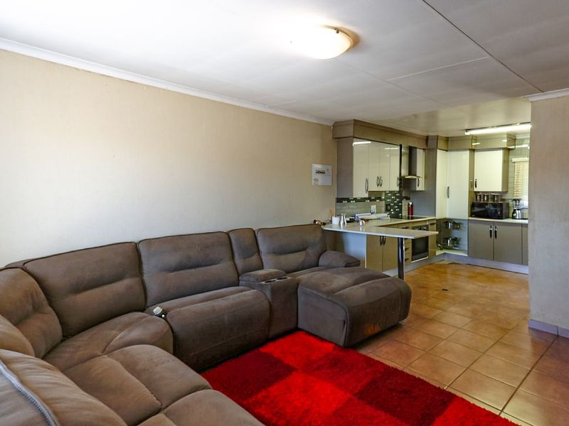 Open-plan living area featuring a functional kitchen with built-in cabinetry, oven, and breakfast bar, seamlessly connected to the main living space with tiled flooring.