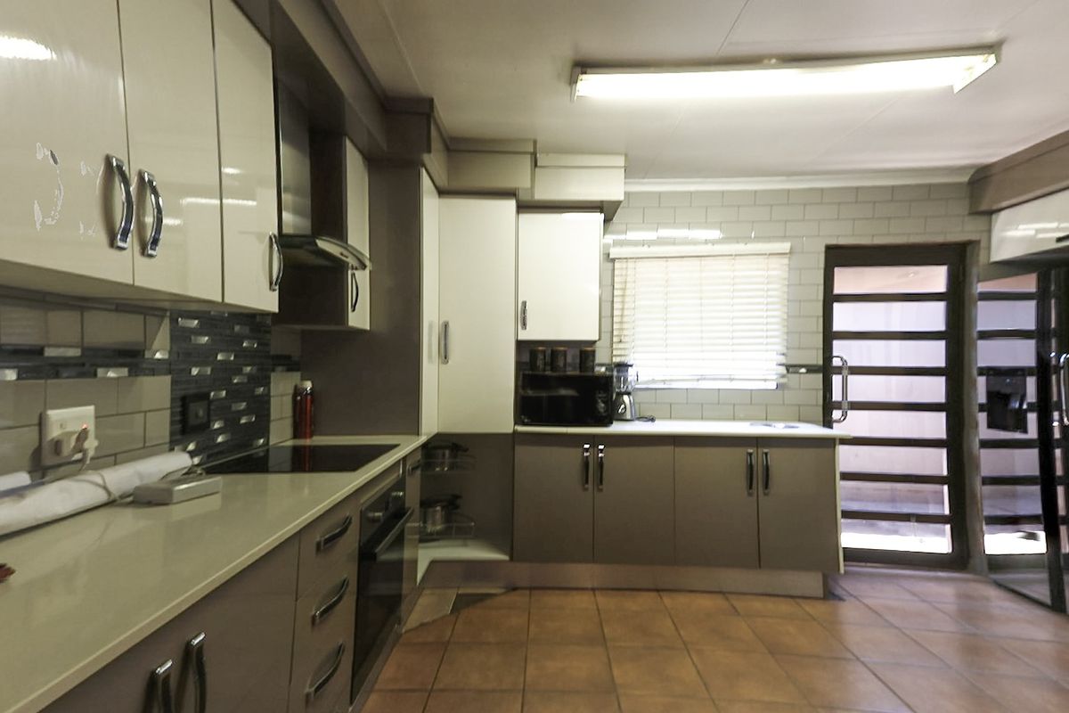 Modern kitchen featuring sleek cabinetry, stone countertops, integrated appliances, subway tile backsplash, and durable ceramic floor tiles with direct access to the exterior.