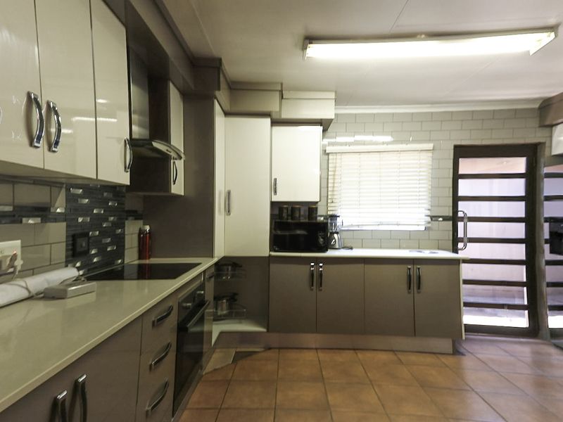 Modern kitchen featuring sleek cabinetry, stone countertops, integrated appliances, subway tile backsplash, and durable ceramic floor tiles with direct access to the exterior.