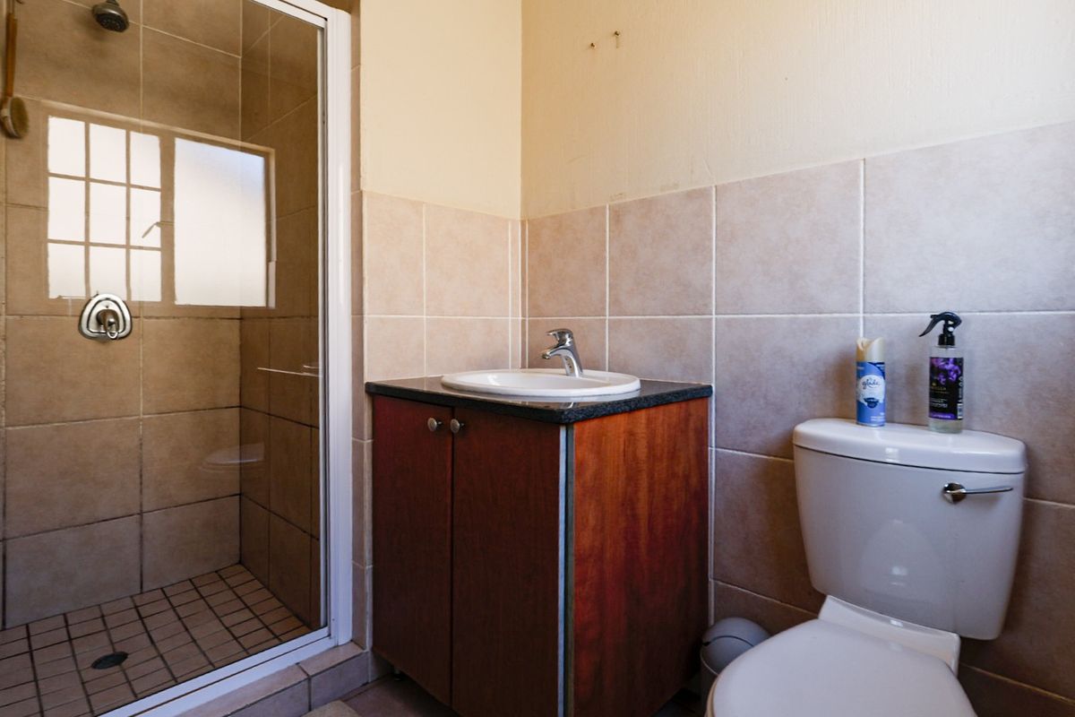 A functional bathroom featuring a tiled shower enclosure, a vanity cabinet with a basin, and a standard toilet.