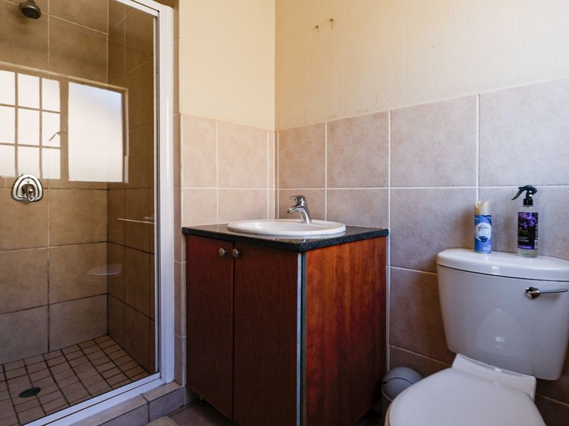 A functional bathroom featuring a tiled shower enclosure, a vanity cabinet with a basin, and a standard toilet.