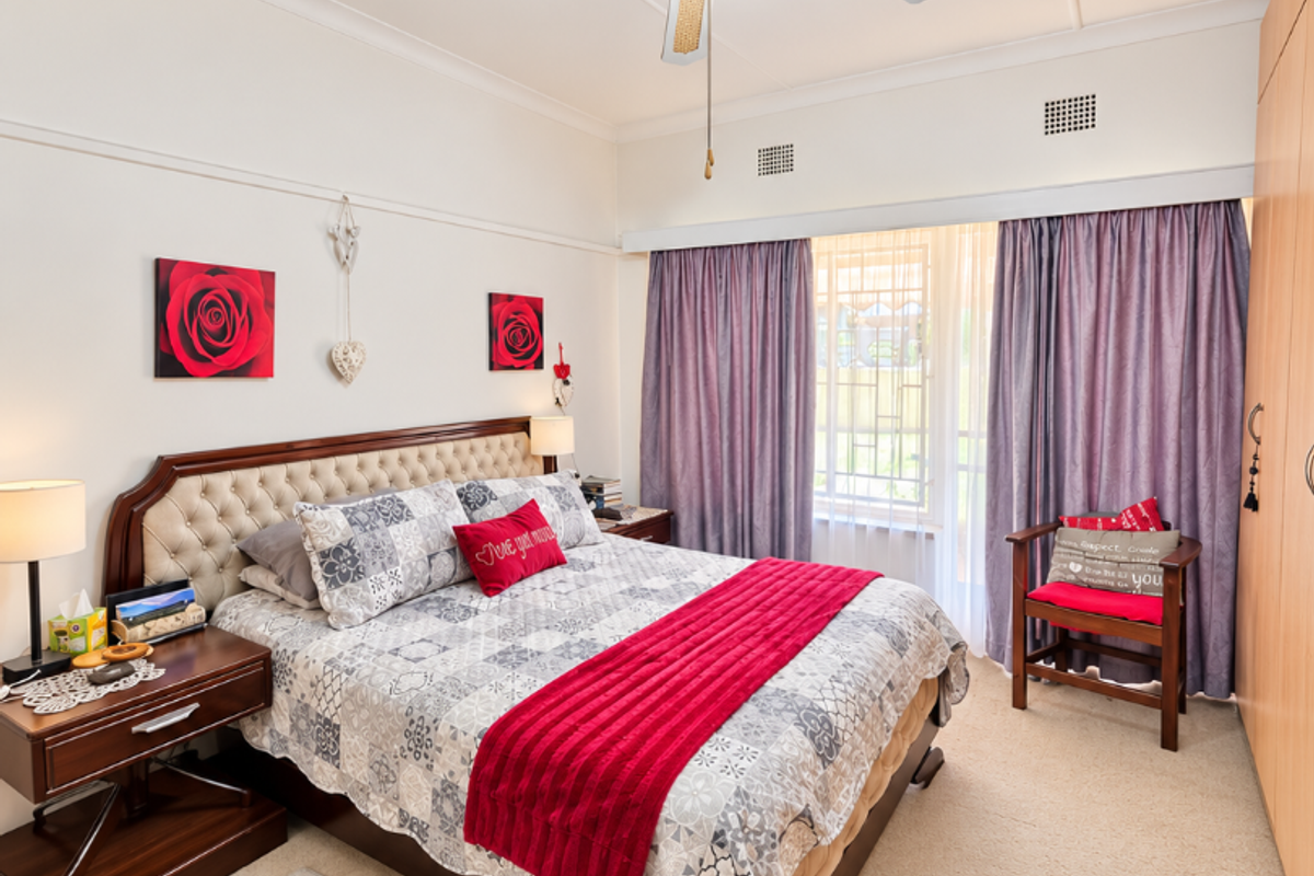 A well-maintained bedroom featuring built-in cupboards, a ceiling fan, and neutral carpeting, offering a comfortable and functional living space.