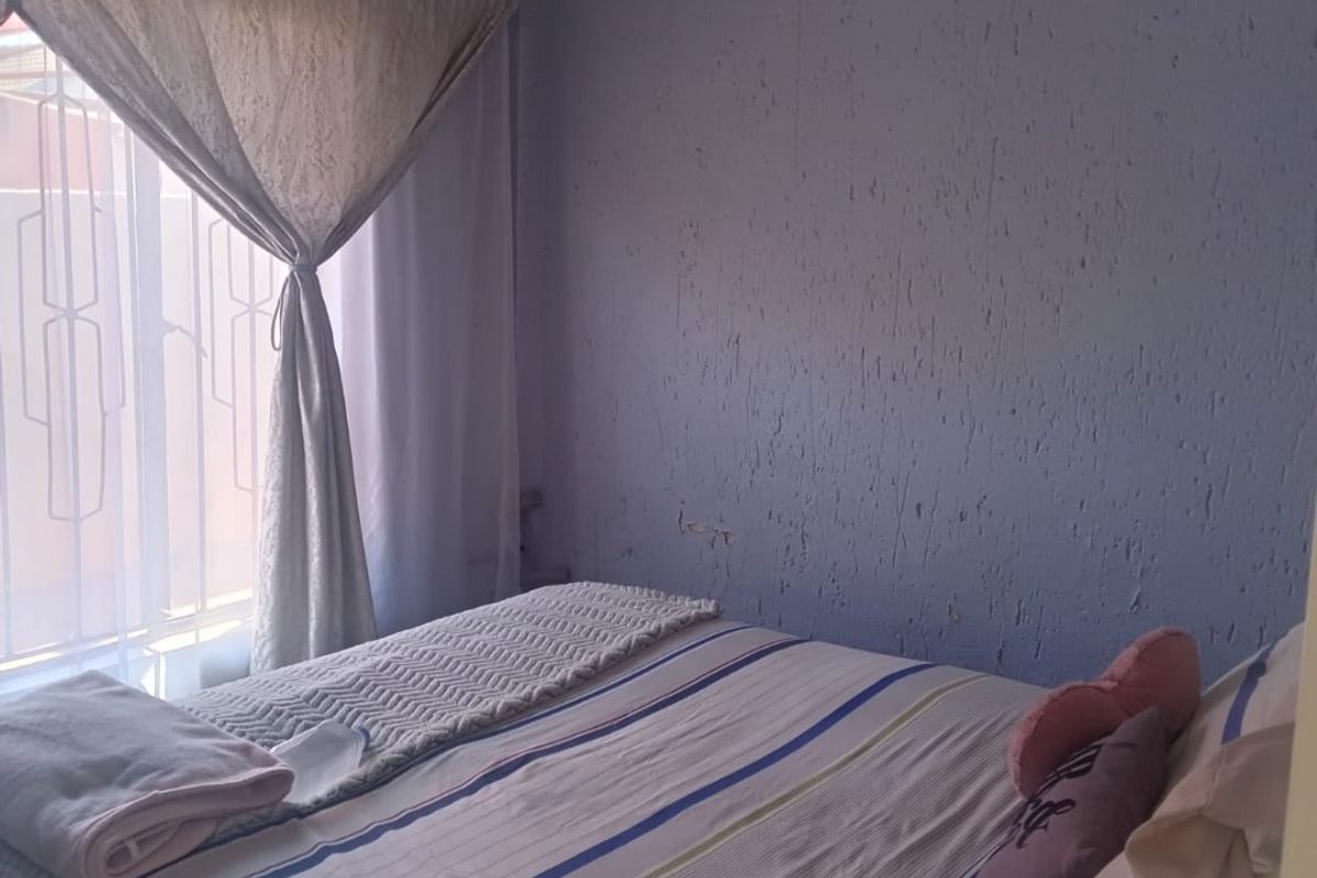 A bedroom featuring textured wall finishes and a window with an integrated security gate.