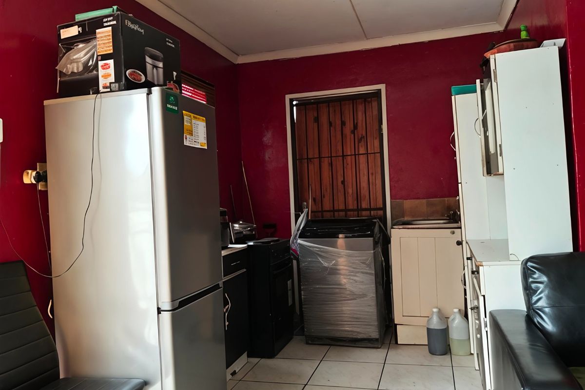 A functional kitchen area featuring tiled flooring, built-in cabinetry, and a sink, with direct access to an exterior security gate.