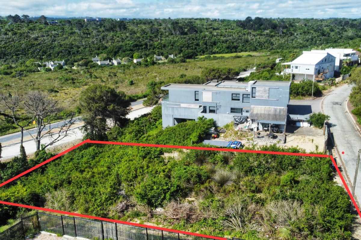 Aerial view of a vacant residential plot featuring natural vegetation and perimeter fencing, situated in a developed neighborhood.