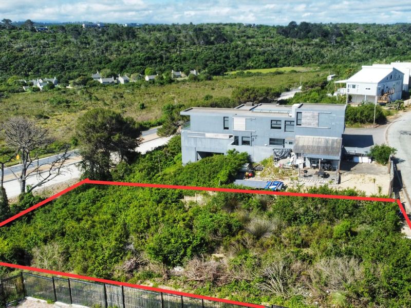 Aerial view of a vacant residential plot featuring natural vegetation and perimeter fencing, situated in a developed neighborhood.