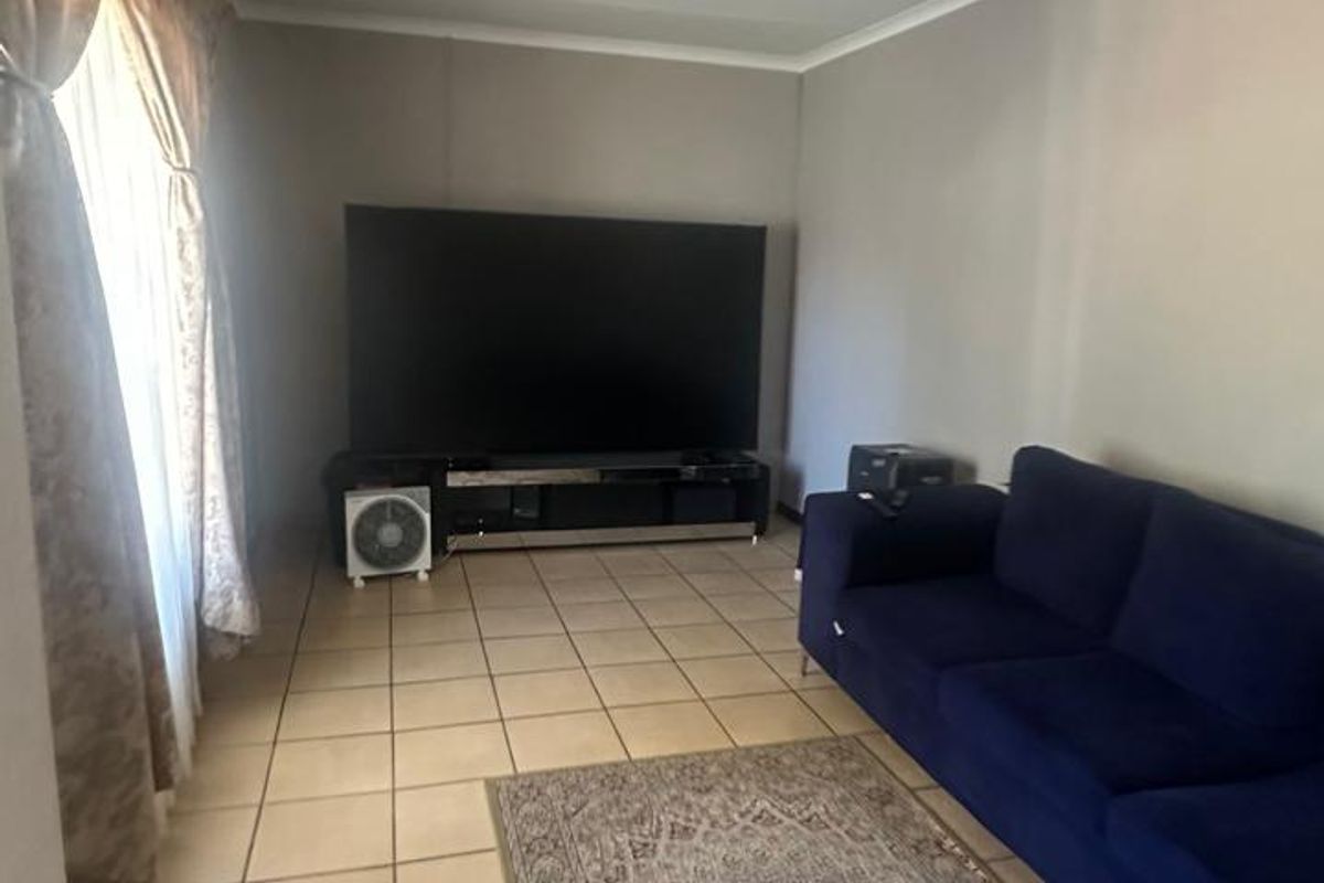 A living room featuring neutral wall tones and tiled flooring, providing a functional and versatile space for relaxation.