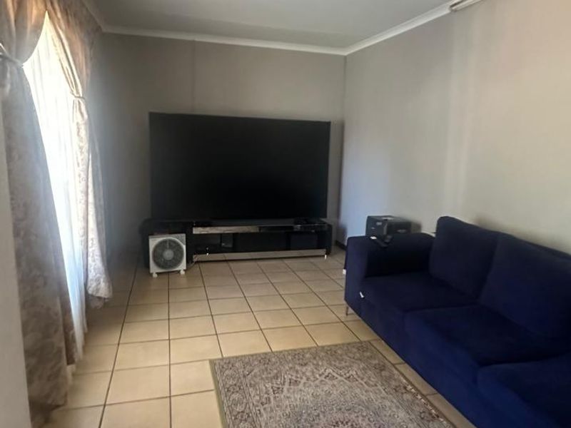 A living room featuring neutral wall tones and tiled flooring, providing a functional and versatile space for relaxation.