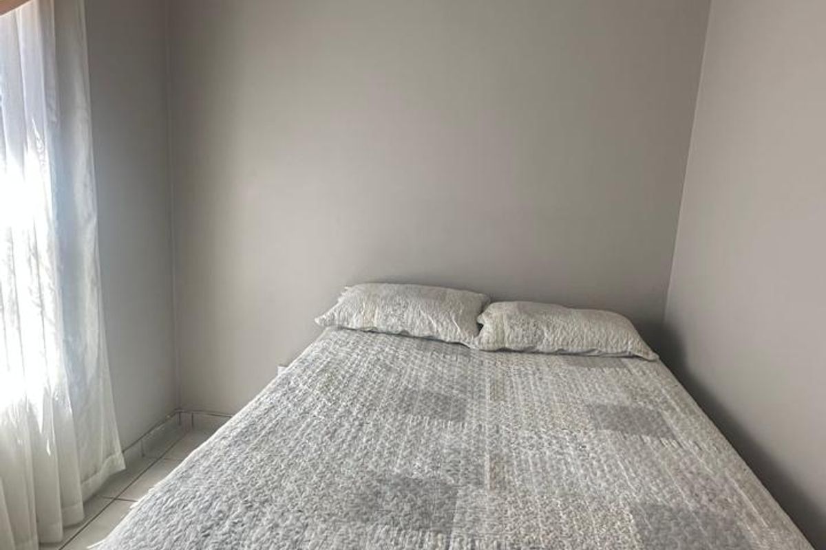 A compact bedroom featuring neutral wall tones, tiled flooring, and recessed ceiling lighting.