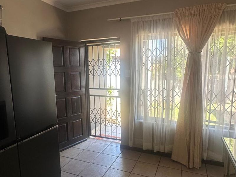An entrance area featuring tiled flooring, a timber door, and a security gate, providing a functional and secure transition space for the home.