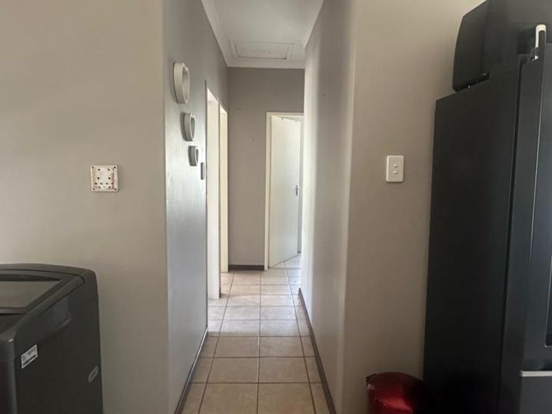 A functional hallway featuring neutral wall paint and tiled flooring, providing access to multiple rooms within the home.