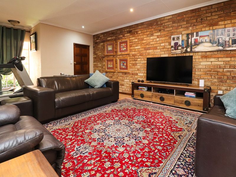 A living room featuring an exposed brick feature wall, recessed downlighting, and a solid timber door.