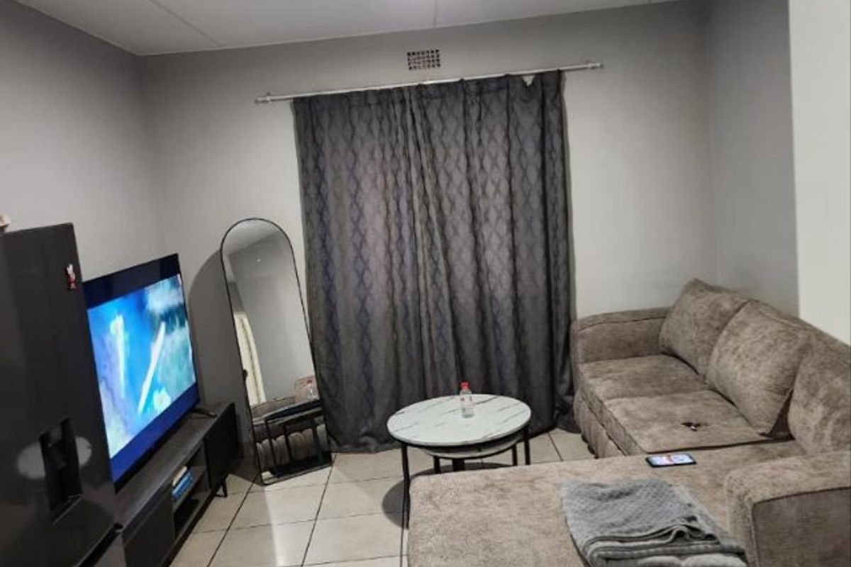 A functional living room featuring neutral tiled flooring and recessed ceiling lighting, providing a clean and practical space for relaxation.