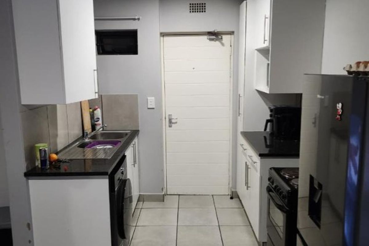 A functional kitchen featuring white cabinetry, dark granite countertops, tiled flooring, and integrated appliances, providing a clean and practical workspace.