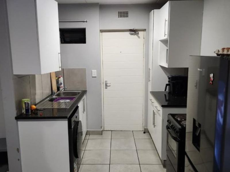 A functional kitchen featuring white cabinetry, dark granite countertops, tiled flooring, and integrated appliances, providing a clean and practical workspace.
