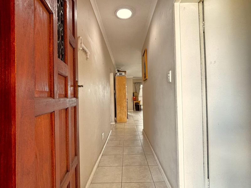 A functional hallway featuring tiled flooring and a wooden entrance door, providing access to the interior living spaces.